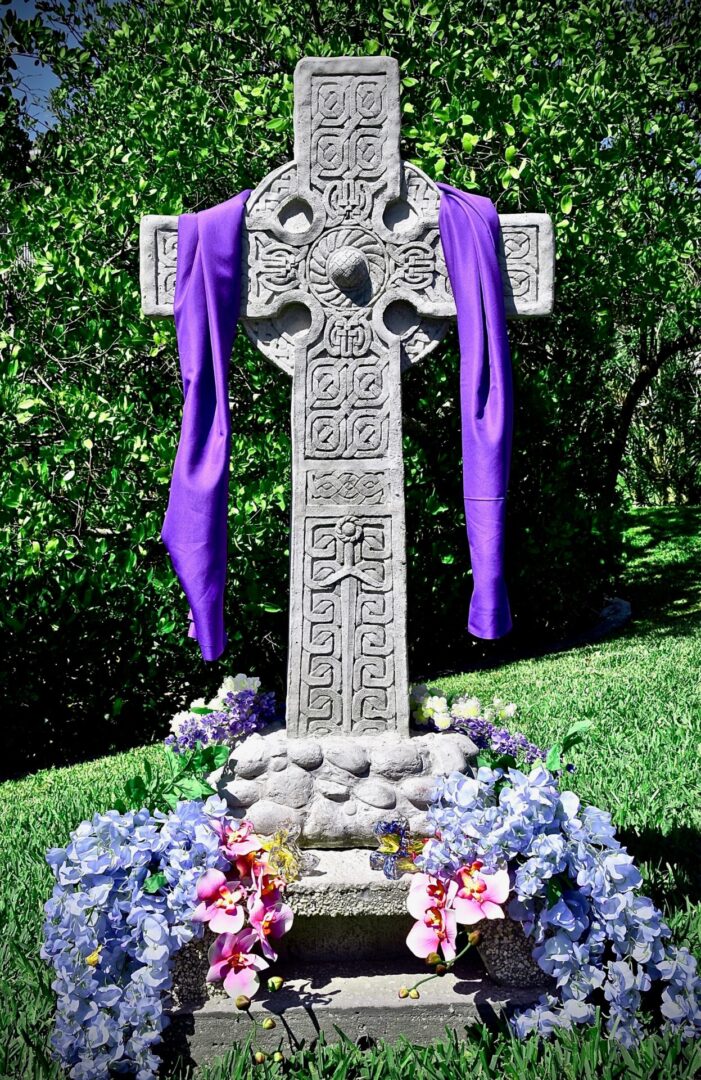 A cross with purple flowers and a blue ribbon.