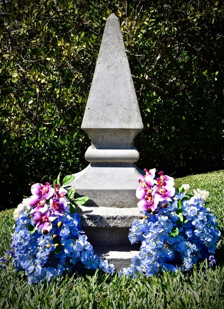 A stone monument with flowers on the side of it.