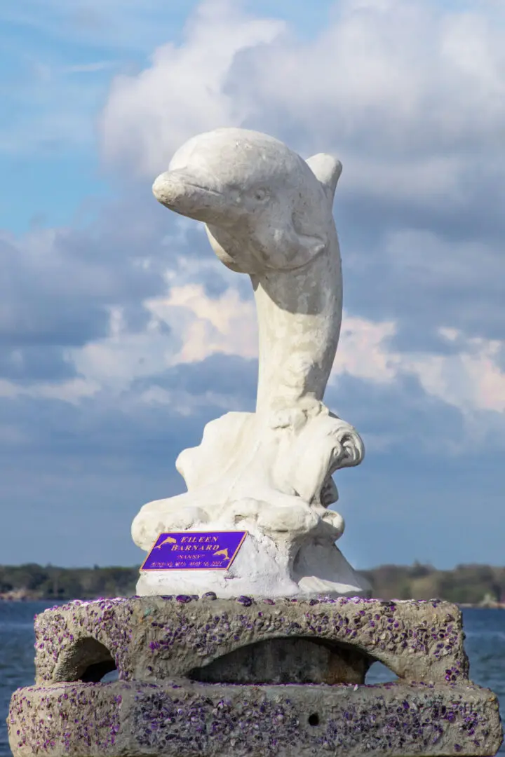 A statue of a dolphin with a purple card in front.